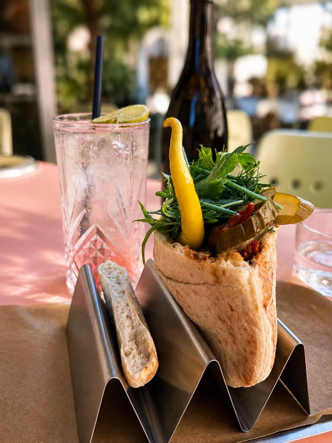 Pita garnie tenue à deux mains, herbes fraîches et pickles qui débordent