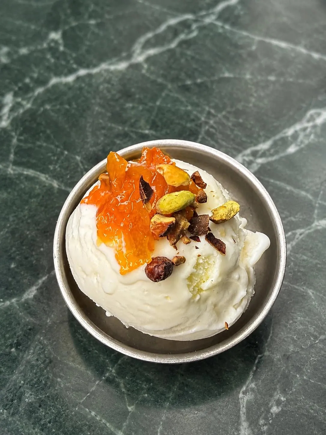 Glace Fior di Latte, kumquat confit et pistache dans une coupelle