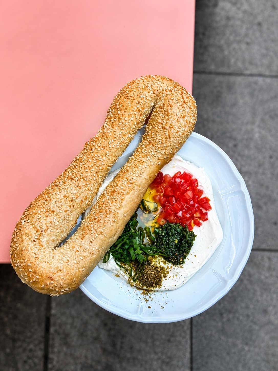 Bagel Jérusalem au sésame posé sur du labneh, tomates, zhoug vert et za'atar