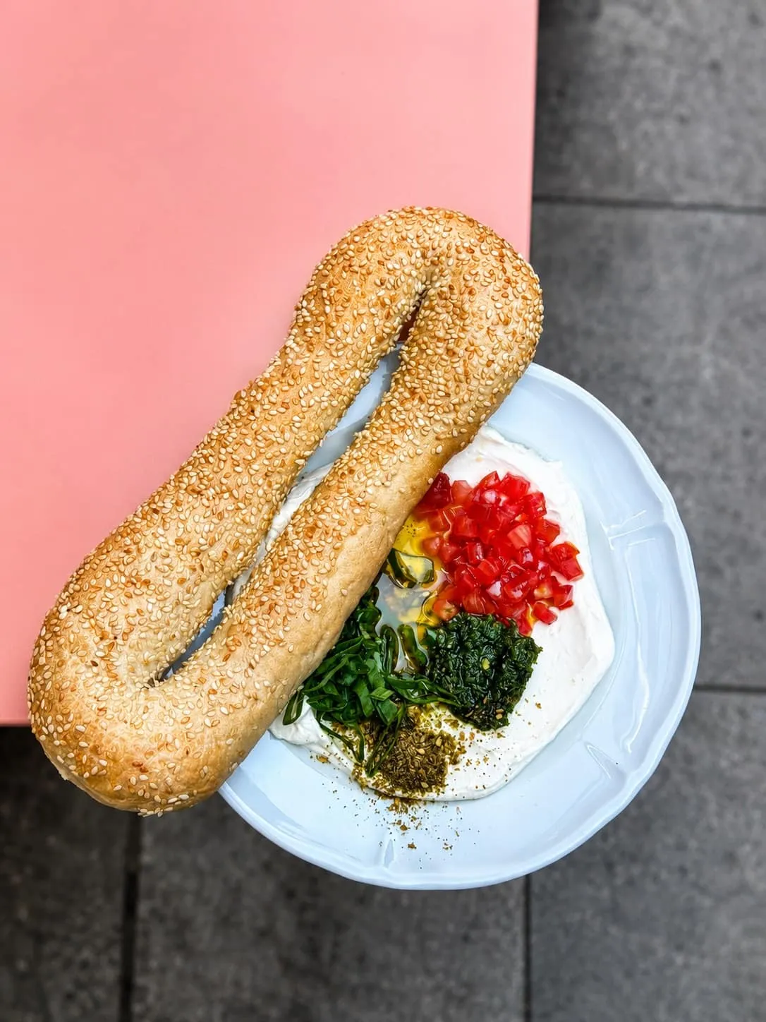 Bagel Jérusalem au sésame posé sur du labneh, tomates, zhoug vert et za'atar