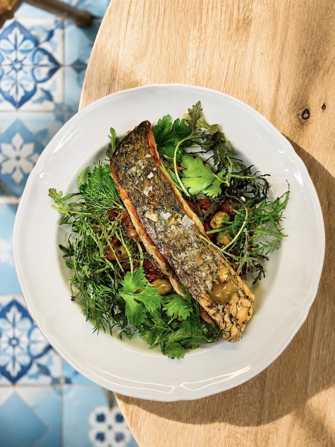 Poisson entier grillé, peau croustillante, sur un lit d'herbes fraîches