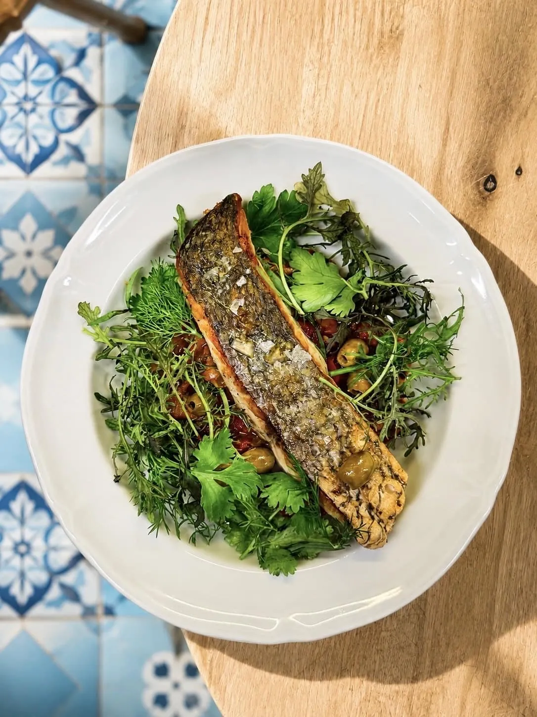 Poisson entier grillé, peau croustillante, sur un lit d'herbes fraîches